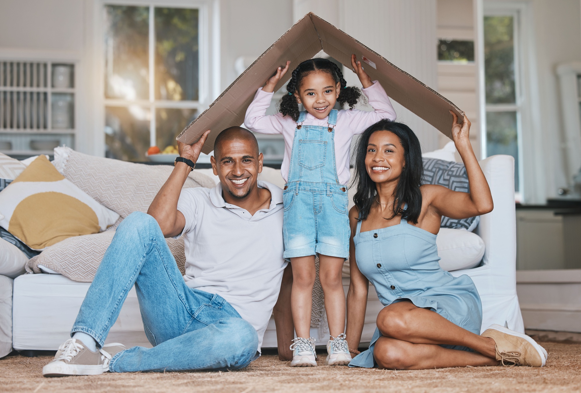 Portrait, cardboard roof and family in the lounge, home insurance and care with protection, smile a